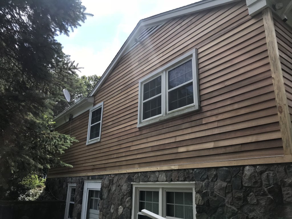 Custom exterior carpentry siding by Ms. Green Construction above modern masonry foundation